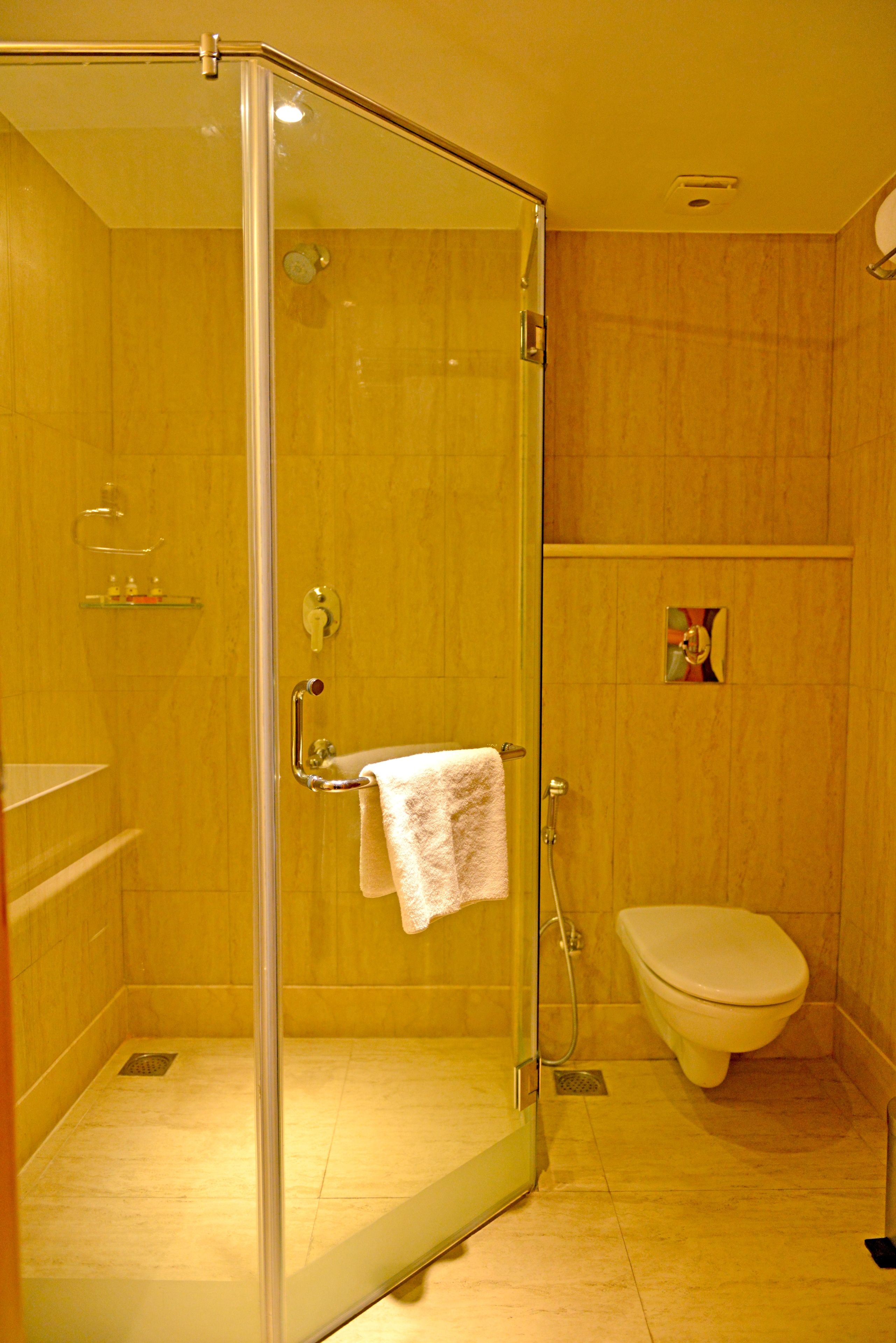 A bathroom with a glass-enclosed shower, a toilet, and a sink.