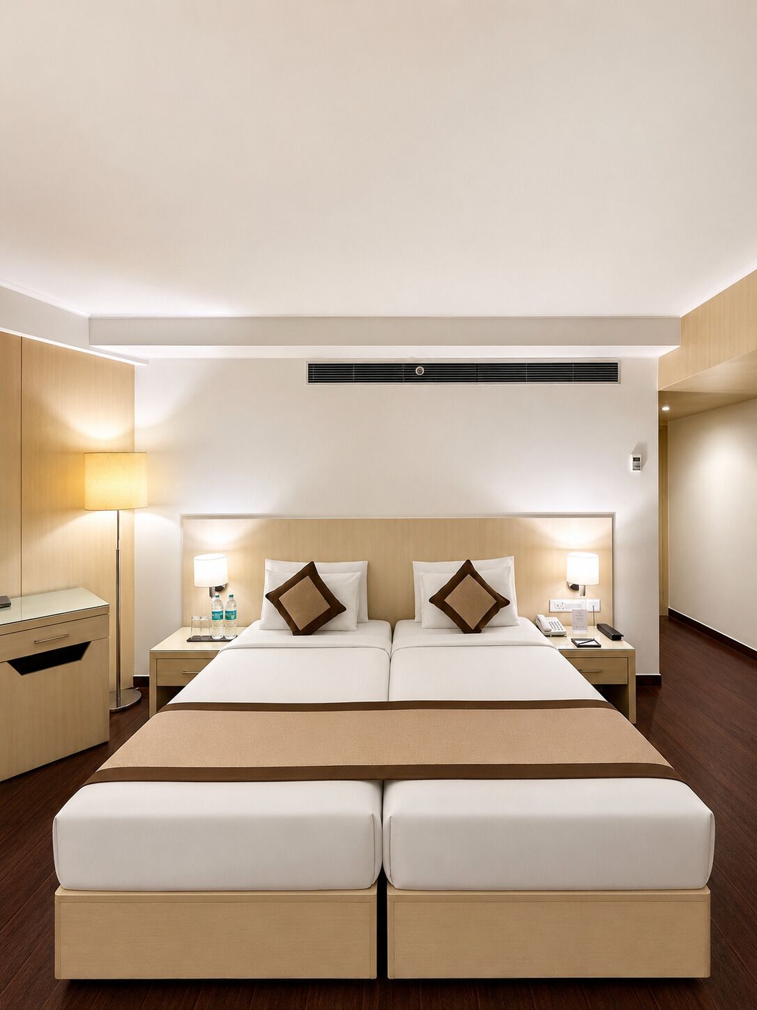 A hotel room with a double bed, bedside tables with lamps, a desk, and a wardrobe.