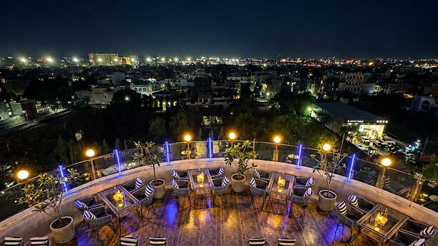 A rooftop bar with outdoor seating, a view of the cityscape, and a pool area. - The Theme Hotel Jaipur (Jaipur)
