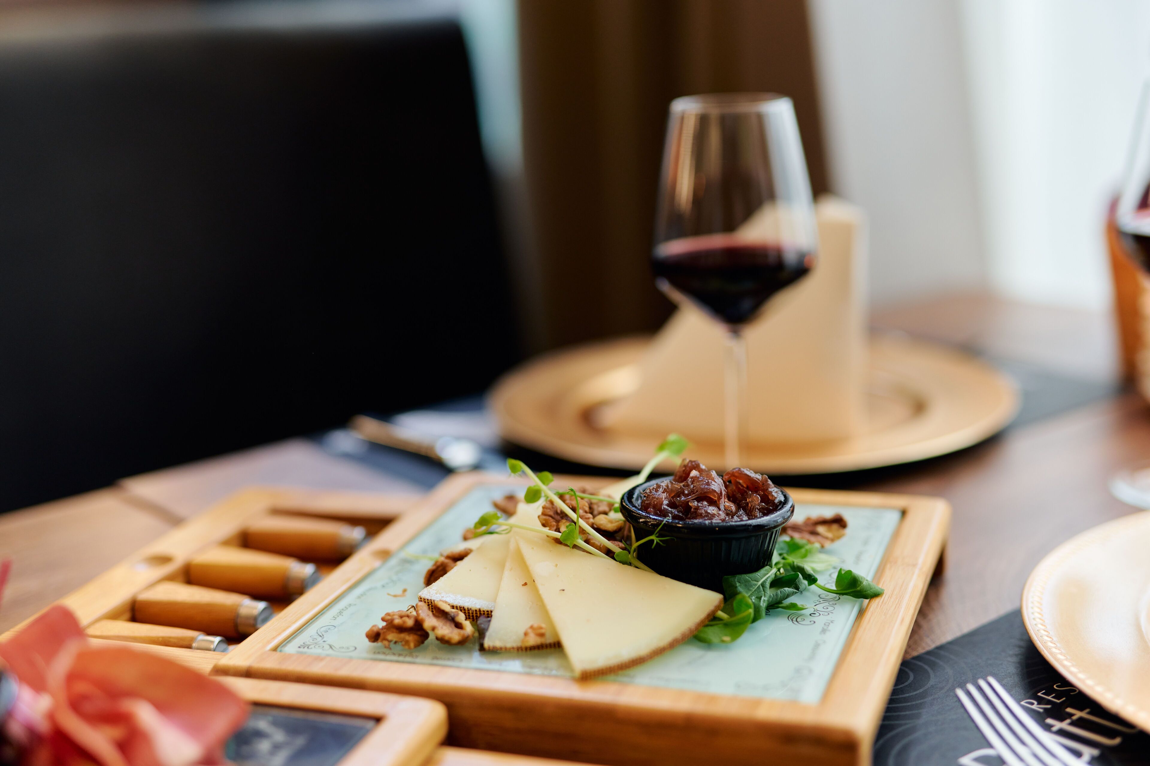 Un tavolo di legno con un tagliere, noci e un bicchiere di vino rosso.