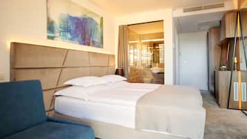 Une chambre d’hôtel moderne avec un grand lit, un fauteuil bleu et un grand tableau abstrait accroché au mur.