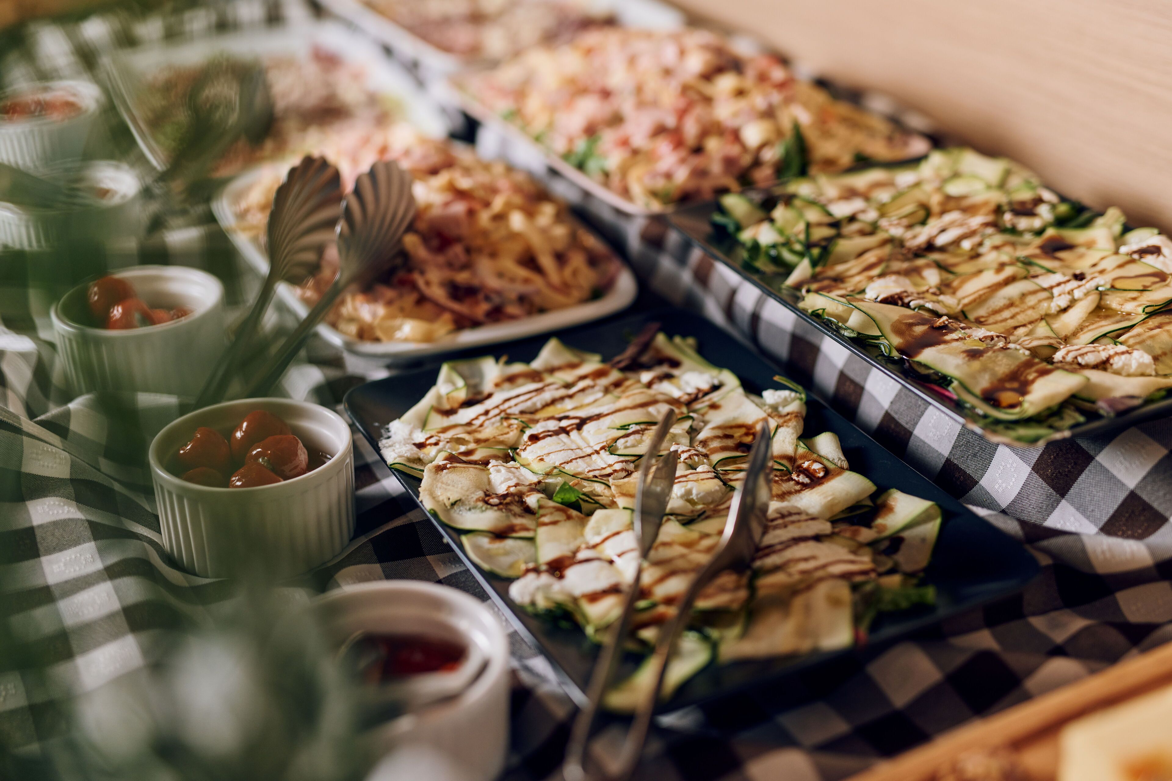 A buffet table with various dishes, including salads, meats, and dips.