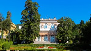 Un edificio histórico con fachada simétrica, amplios ventanales y una entrada central.