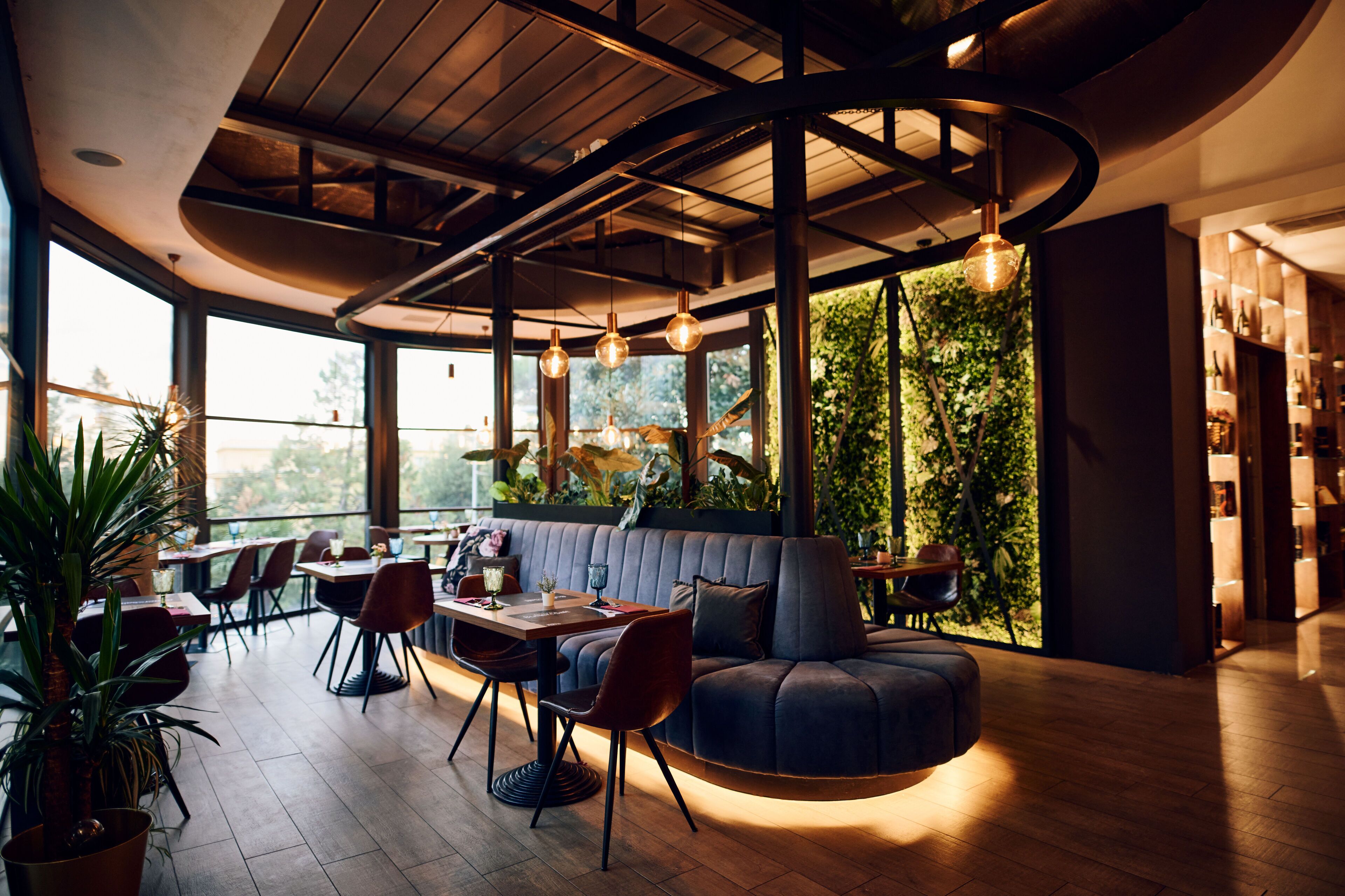 Un intérieur moderne avec un plafond incurvé, de grandes fenêtres et un espace salon comprenant un canapé et des fauteuils.