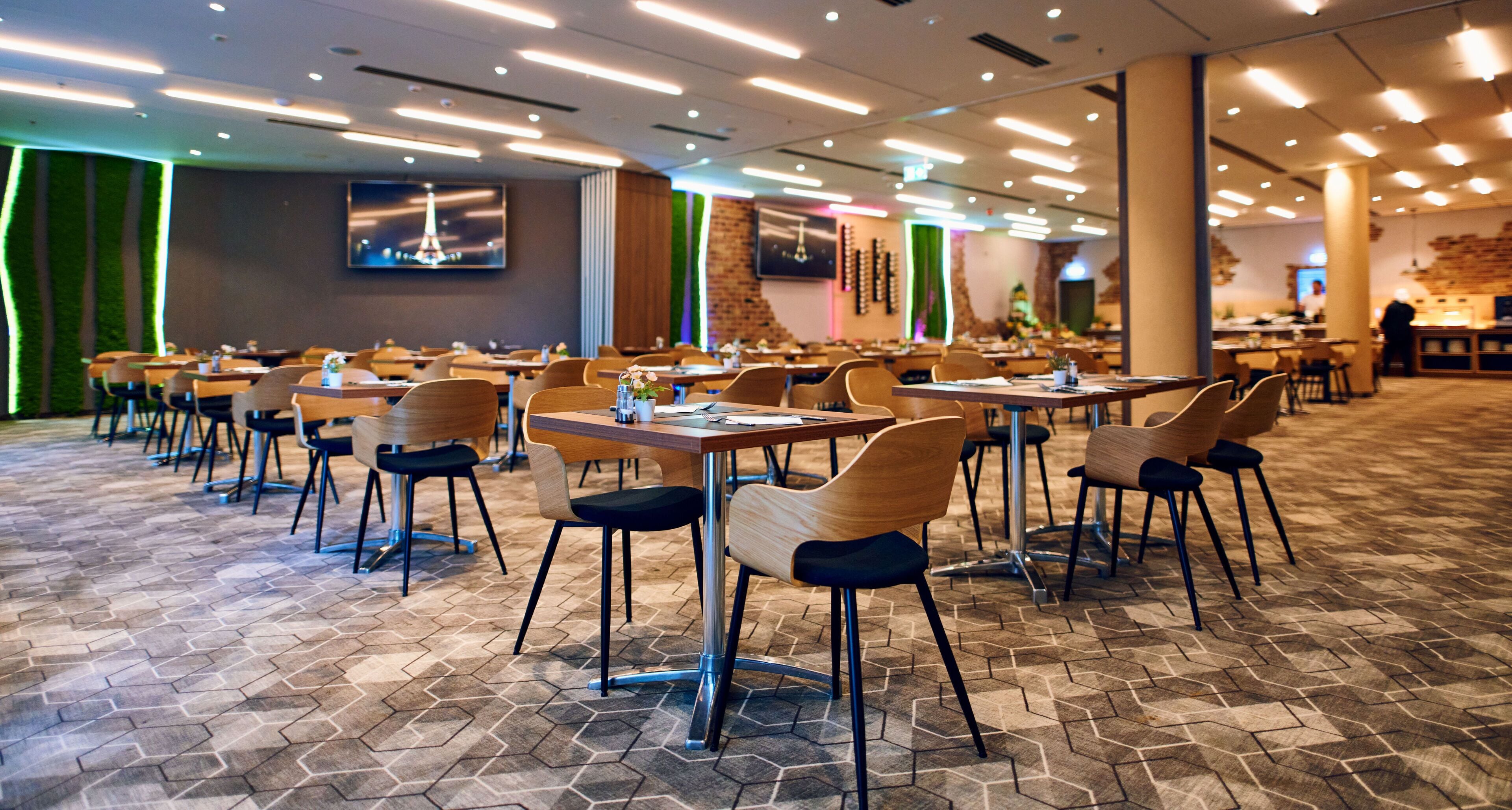 A spacious dining area with hexagonal patterned flooring, wooden tables, and chairs.