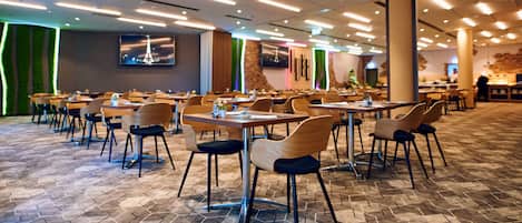 A spacious dining area with hexagonal patterned flooring, wooden tables, and chairs.