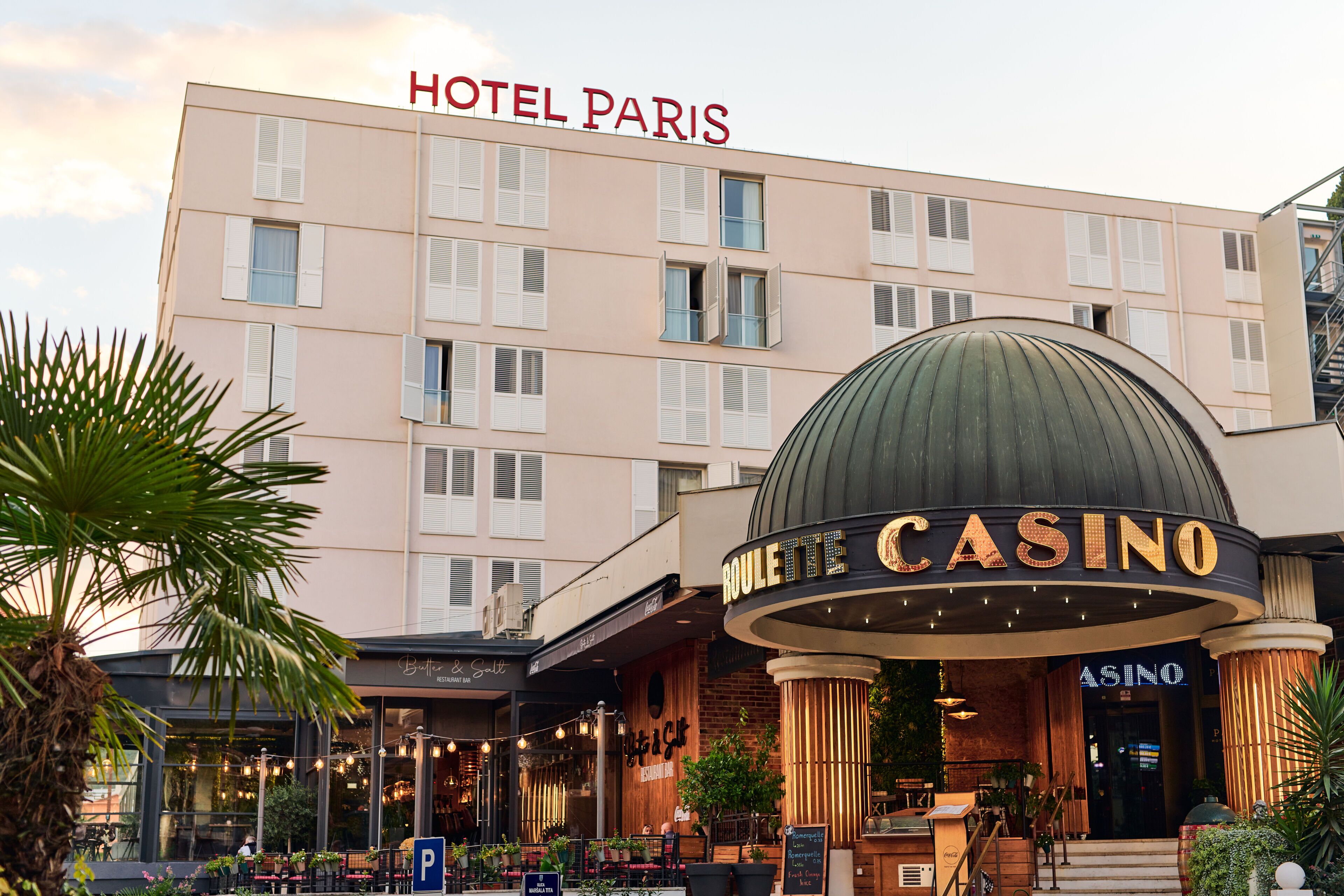 A hotel with a casino, featuring a large sign for the casino and a prominent "HOTEL PARIS" sign above the building.