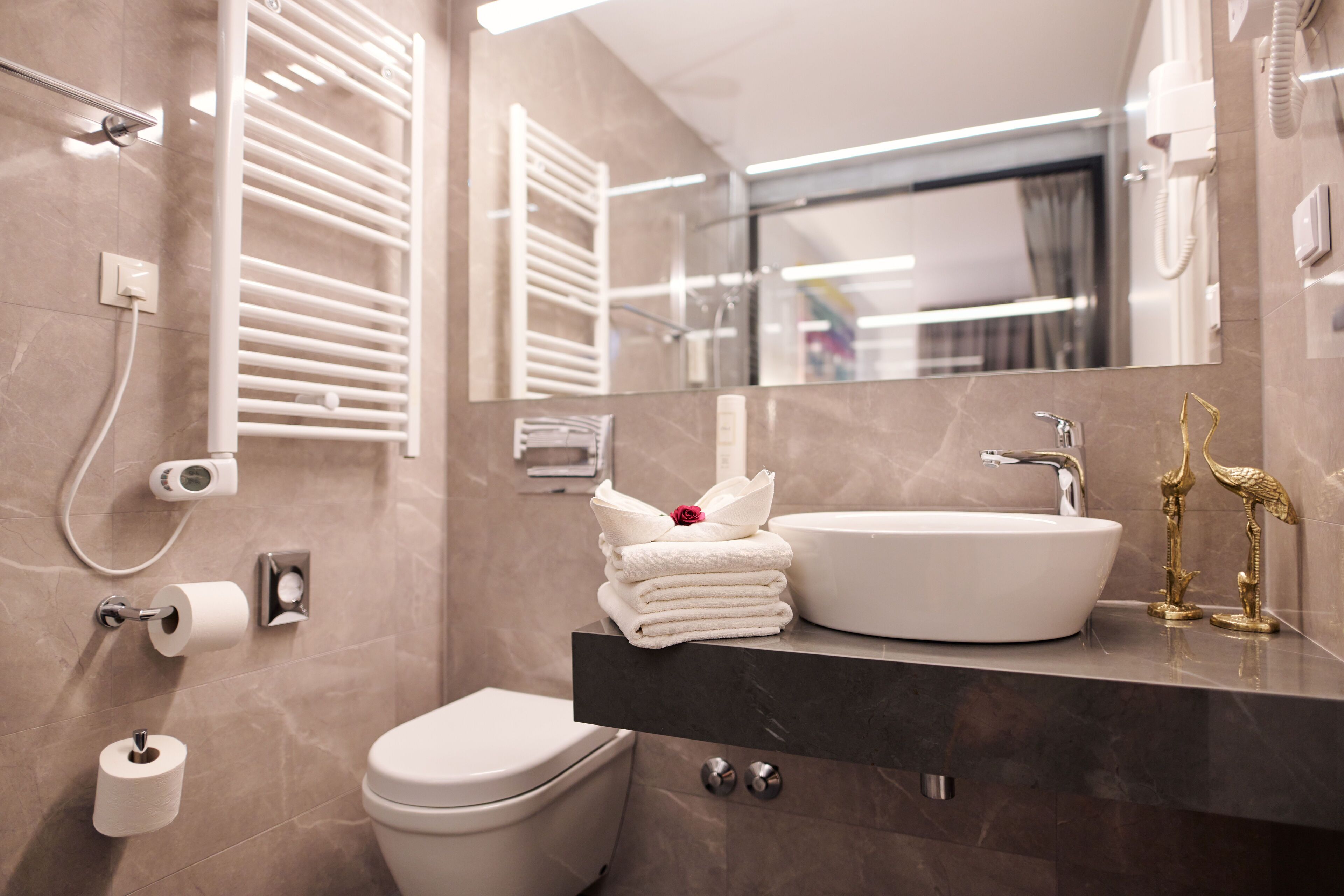 A modern bathroom with a toilet, sink, towel stack, and a mirror.