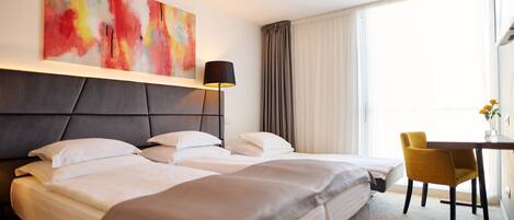A hotel room with two beds, a desk, a chair, and a large abstract painting on the wall.