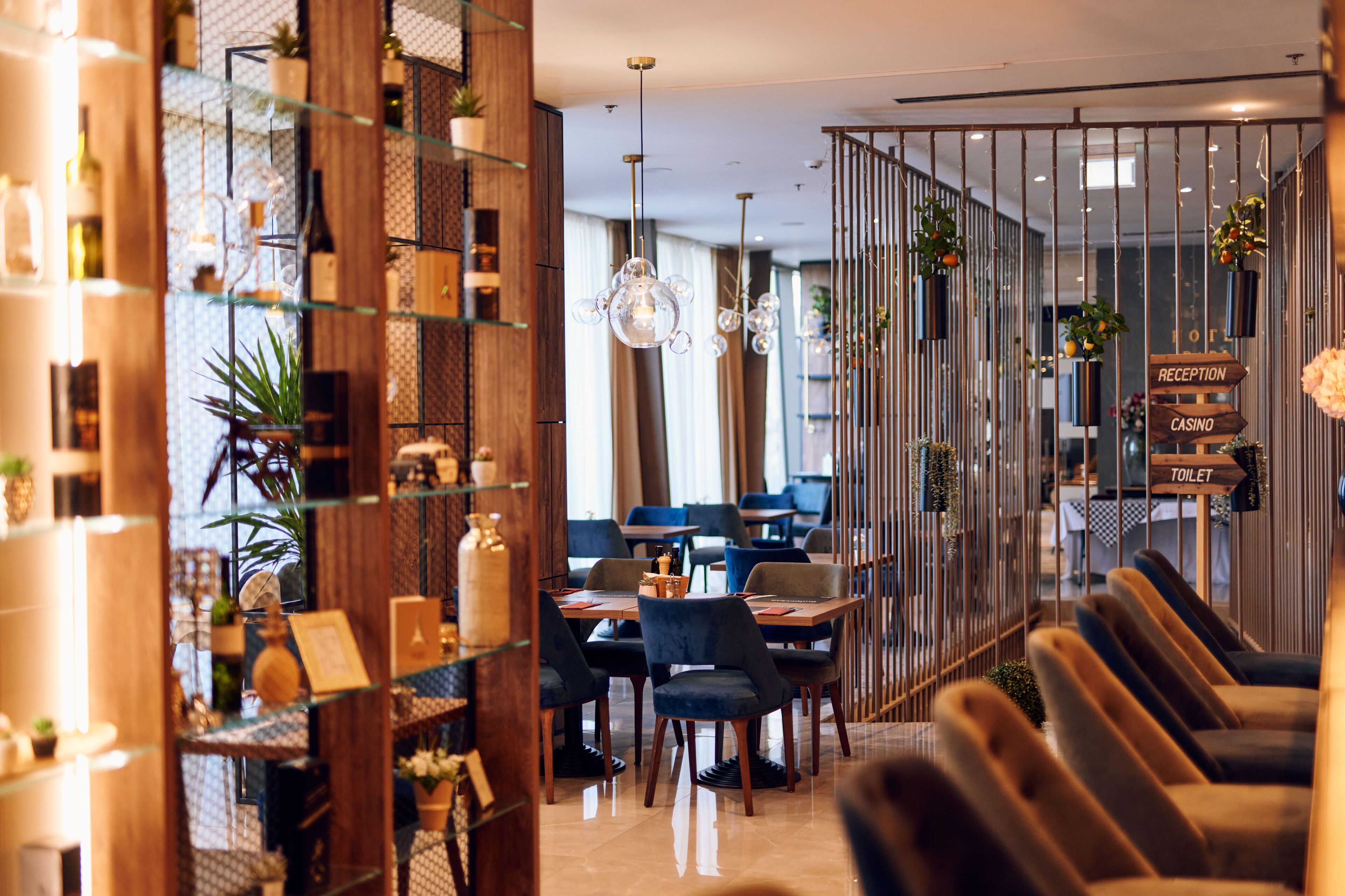 Un interior moderno con mostrador de recepción, zona de estar y señalización que indica recepción, casino y baño.