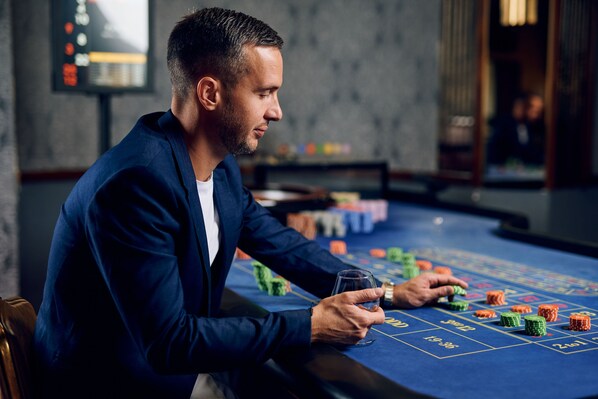 Un hombre jugando blackjack en una mesa de casino, con fichas y cartas.