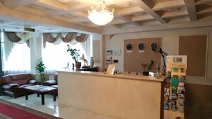 Et hotellets receptionområde med en reception, en lysekrone, en sofa og et sofabord.