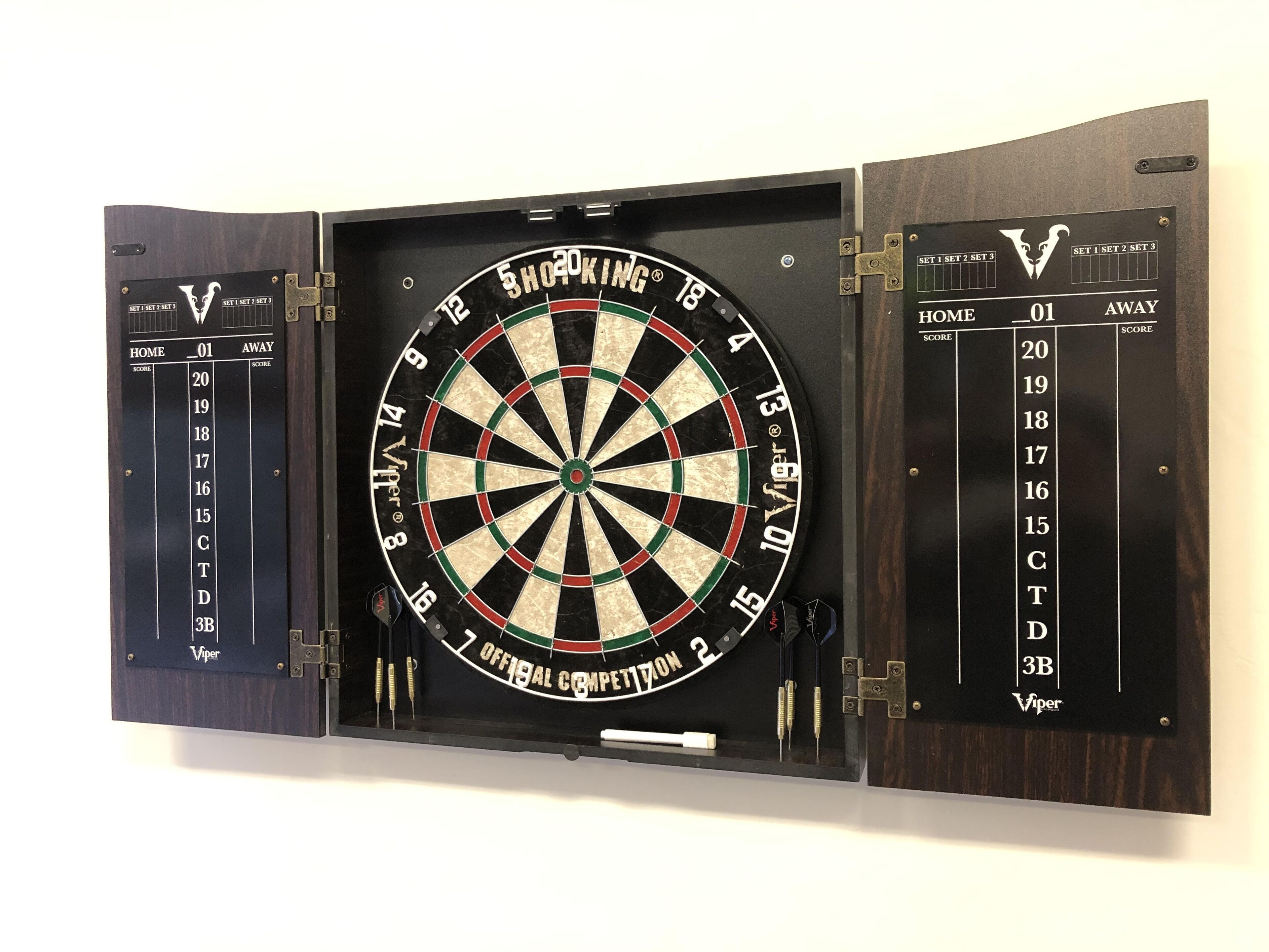 Une cible de fléchettes fixée au mur, avec des tableaux de pointage de chaque côté.