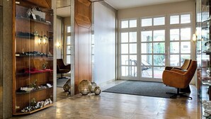 A spacious lobby with a high ceiling, large windows, and a modern wooden shelving unit. - Hotel Engbert (Oelde)