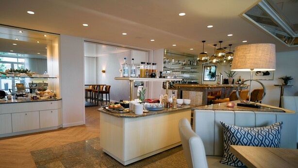 A modern kitchen with a central island, bar area, seating, and a dining area. - Hotel Engbert (Oelde)
