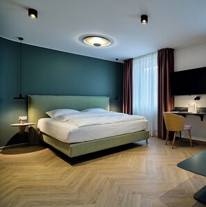 Une chambre d’hôtel moderne équipée d’un grand lit, d’un bureau avec une chaise, d’une télévision et d’un luminaire au plafond.