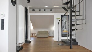 Ein modernes Interieur mit Holzboden, einer Treppe, einem Bett und einer Heizung.