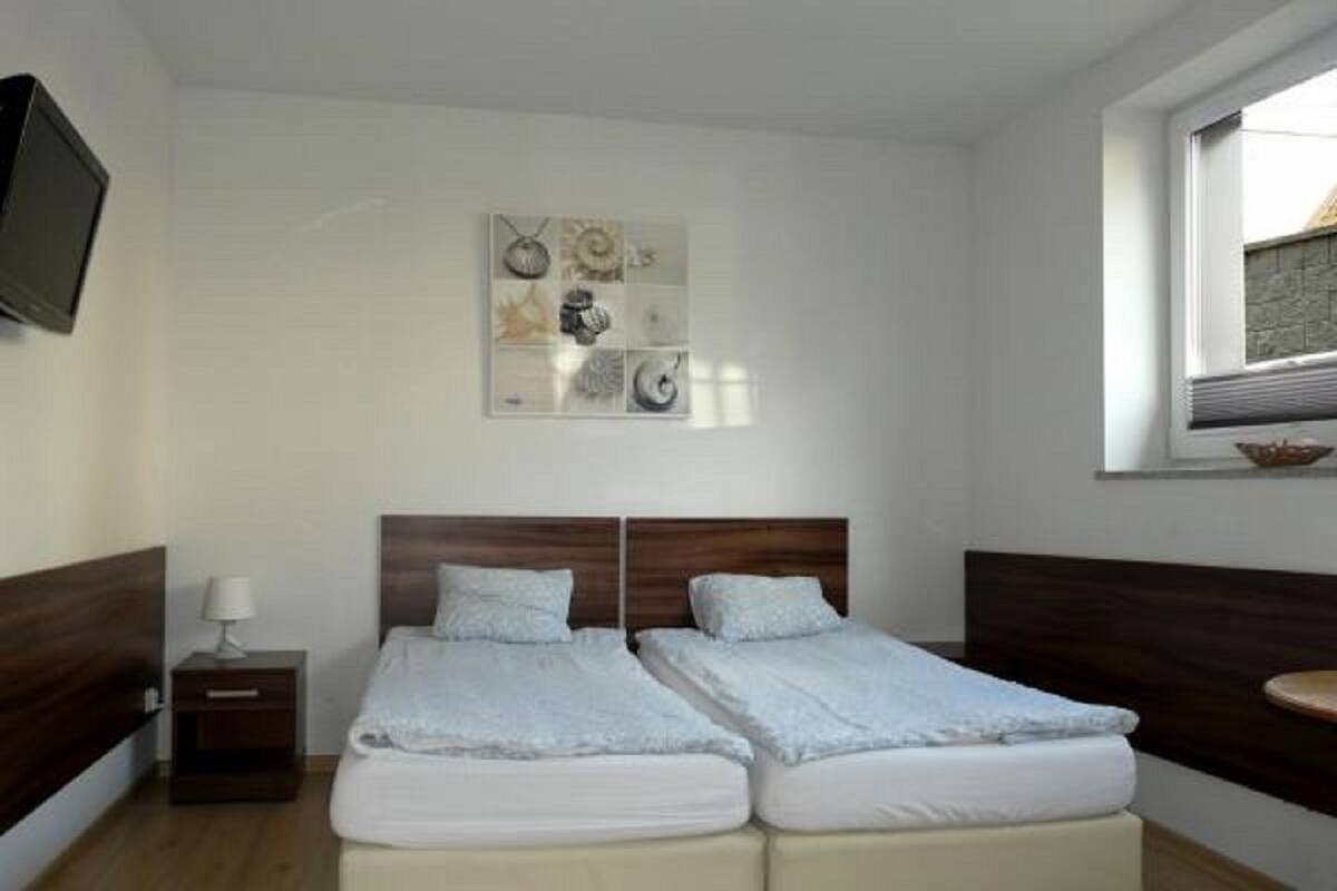 Una cama doble con cabecera de madera, una mesita de noche con lámpara y una obra de arte colgada en la pared.