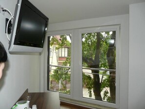 A room with a large window, a mounted television, and a wooden floor. - Amber House (Gdansk)