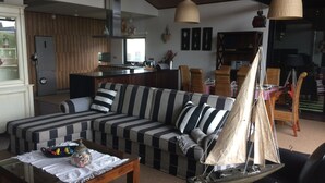 En stue med en stribet sofa, et sofabord og en modelsejlads.