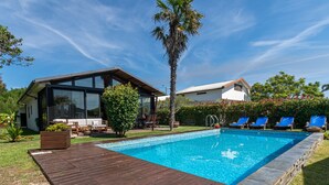 Et moderne hus med swimmingpool, terrasse og patio med udendørs møbler.
