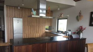 Et moderne køkken med en træø, rustfrie hvidevarer og et stort vindue med naturligt lys.