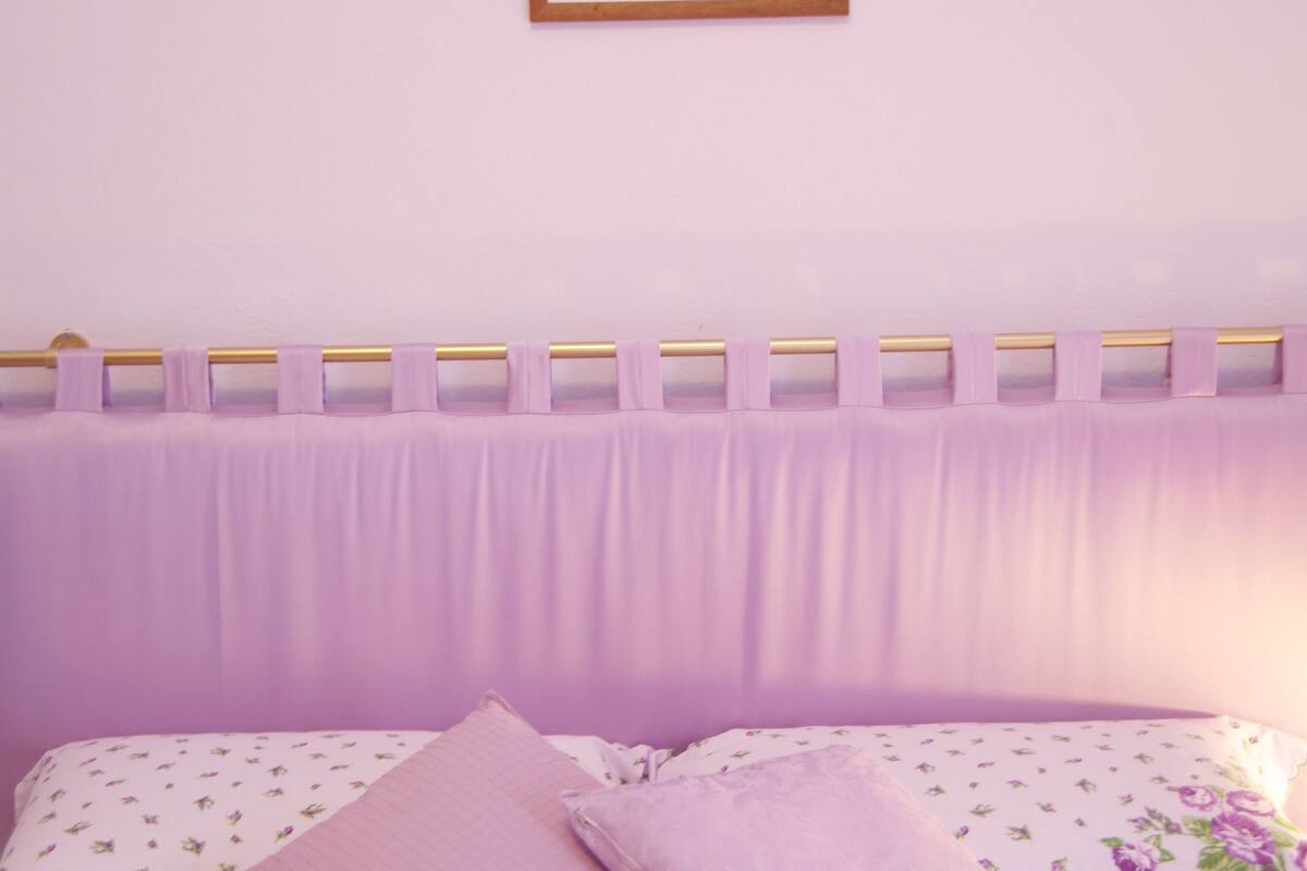 A bedroom with a bed, pillows, a headboard, and a framed picture on the wall.