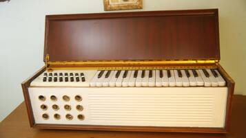 An upright piano with a wooden finish and a white body, placed on a wooden surface.