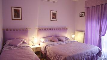 A room with two beds, each with a headboard, a nightstand, a lamp, and a framed picture on the wall.
