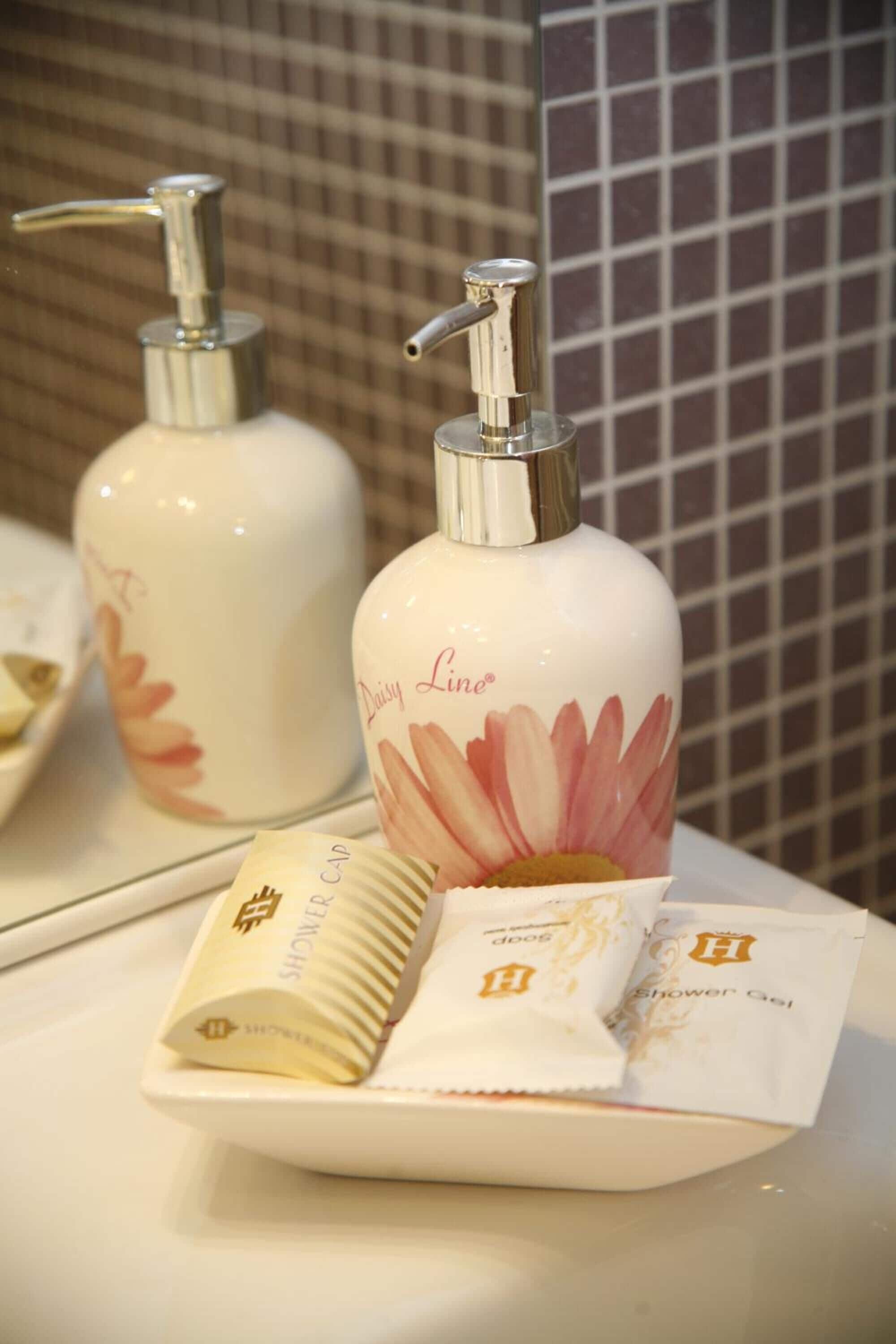 A bathroom with a white sink, two bottles of shower gel, and a hand towel.
