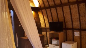 A cozy room with a bed, a television, a small cabinet, and a heater. - Sandy Beach Bungalows (Gili Air)