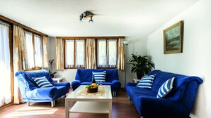 Una sala de estar con dos sofás azules, una mesa de centro y un cuadro en la pared.