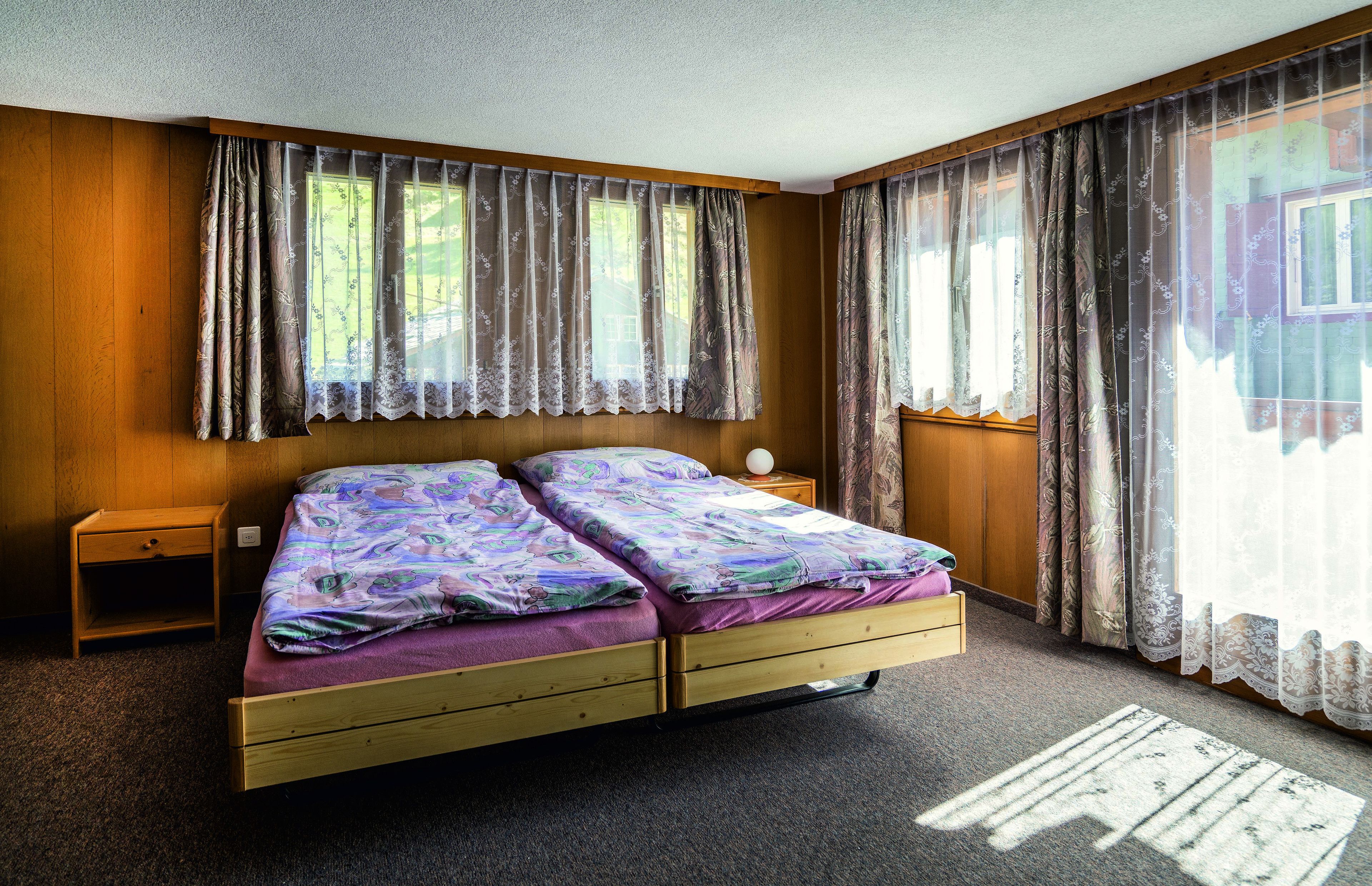 A bedroom with a wooden bed, two nightstands, and curtains.