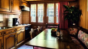 Una cocina de madera con una mesa de comedor, sillas, una cafetera y un bol de fruta.