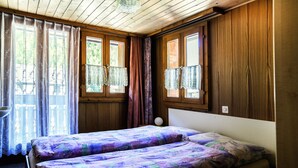 Una habitación con dos camas, paredes de madera y una ventana con cortinas.
