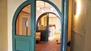 A green door leading into a room with a herringbone floor and a chair. - dieSonne (Weimar)