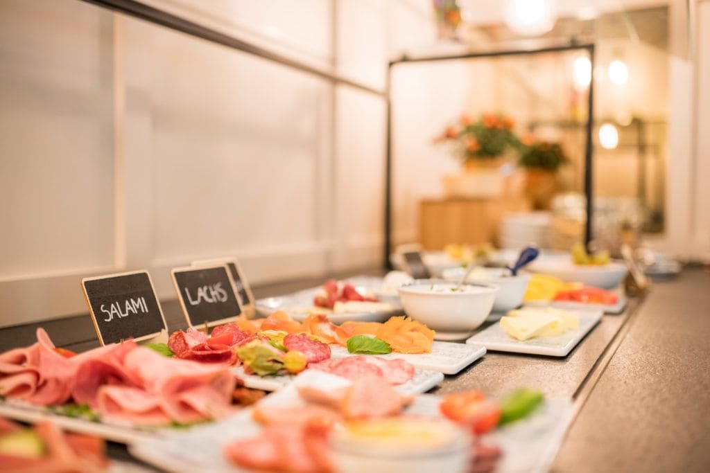 Un bufé con diversas carnes y quesos, incluyendo etiquetas que dicen 'SALAMI' y 'LACIS'.