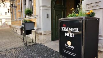 Un cartel negro con la inscripción 'ZIMMER FREI' e información de contacto para una propiedad llamada 'die-sonne-weimart.de'.