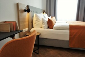 A hotel room with a bed, a desk, and a chair. - dieSonne (Weimar)