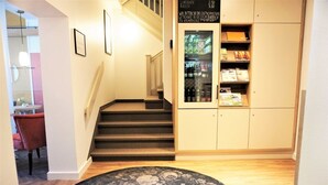 A staircase leading to a landing with a small table and a chair, a bookshelf with various items, and a patterned rug on the floor. - dieSonne (Weimar)
