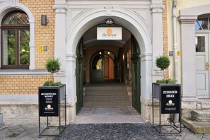 An entrance to a building with a sign reading "de Sonne" above the door. There are two signs on either side of the entrance, one for a buffet and the other for a room with a view. - dieSonne (Weimar)