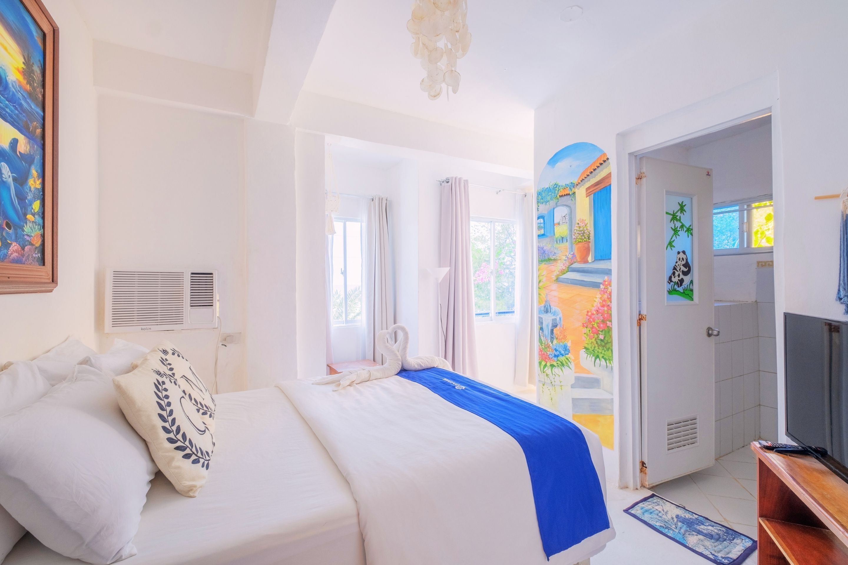 A hotel room with a bed, a television, and a door leading to another room.