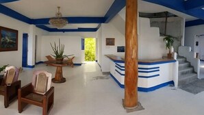 Un amplio vestíbulo con una recepción, una escalera y una gran columna de madera.