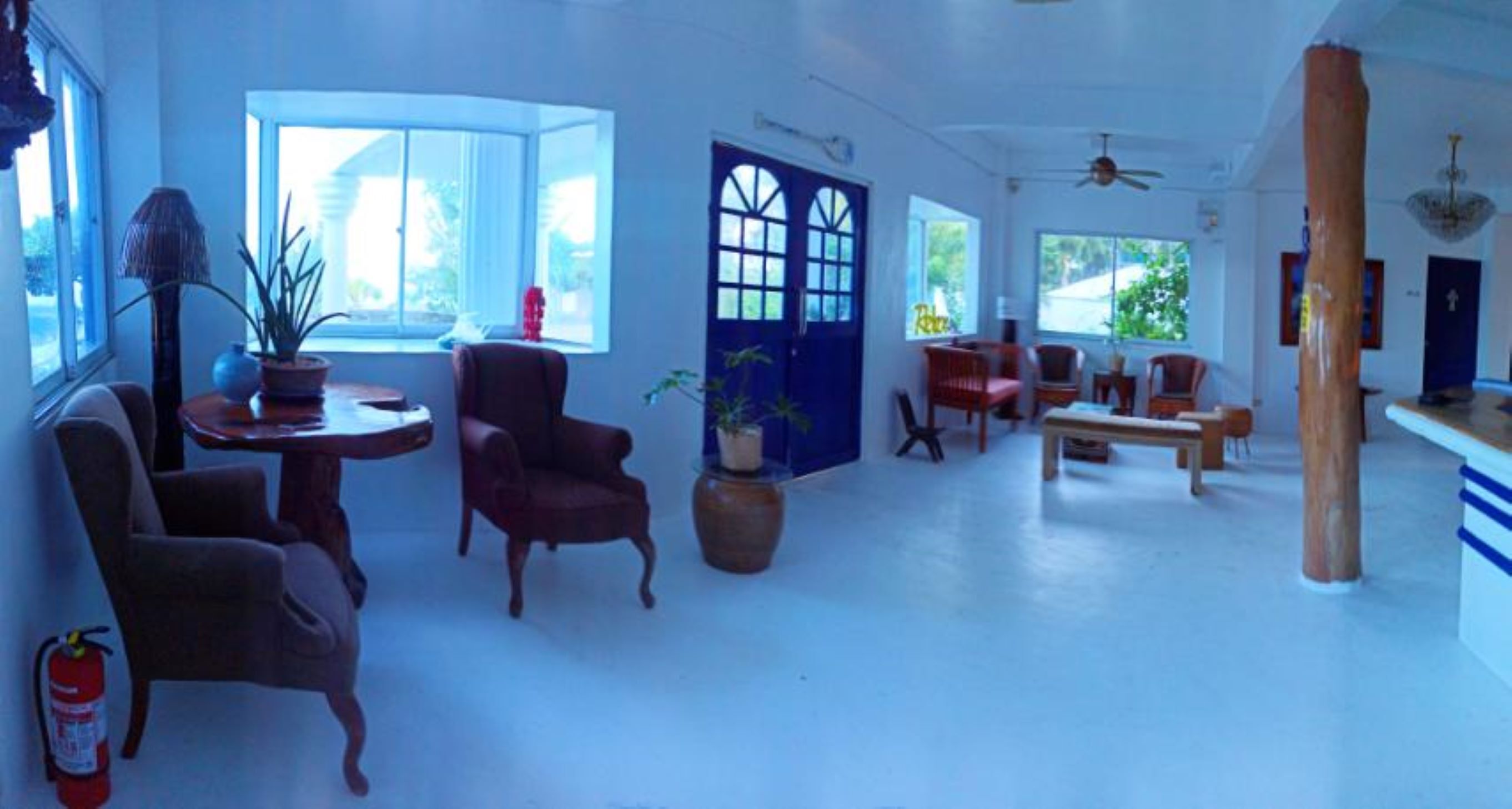 A spacious room with large windows, a blue door, and a ceiling fan.