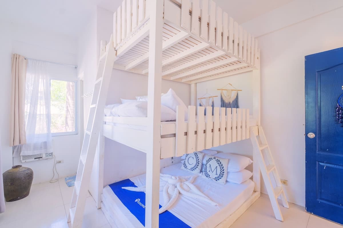 Une chambre avec un lit superposé, une échelle, un tapis bleu et une armoire à porte bleue.