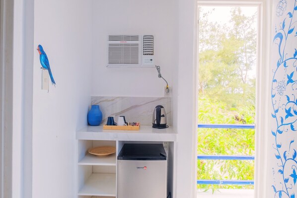 A compact kitchenette with a refrigerator, a kettle, and a blue vase on the counter. - Club Monet Beach Resort By Cocotel (Cabangan)