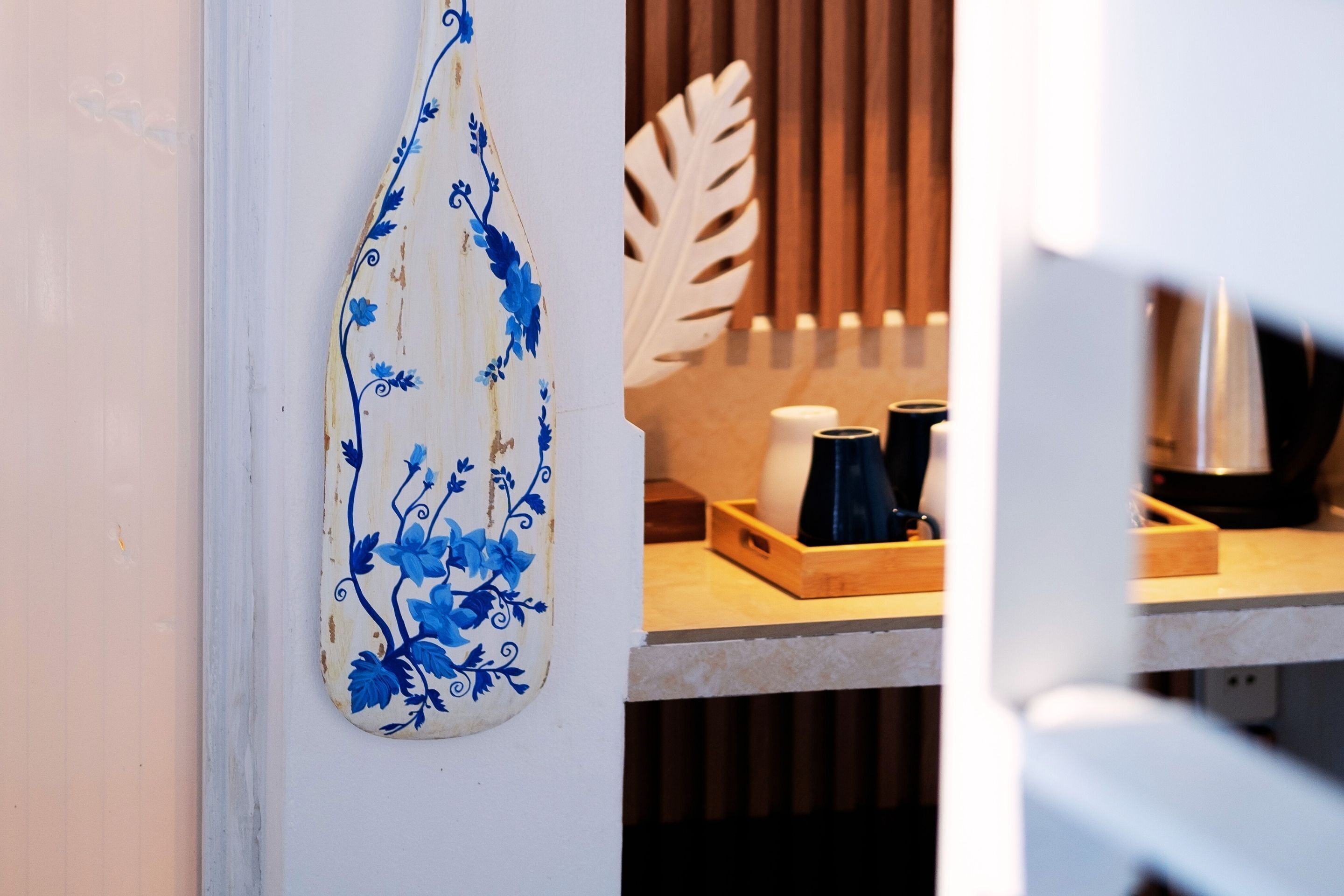 A kitchen counter with a decorative ceramic piece, a wooden leaf-shaped object, and a tray with items.