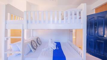 Habitación con literas, una toalla azul y almohadas, una puerta blanca y un adorno en el techo.