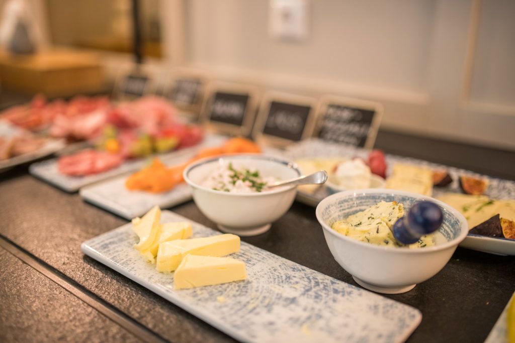 A buffet with various food items including cheese, dips, and meats.