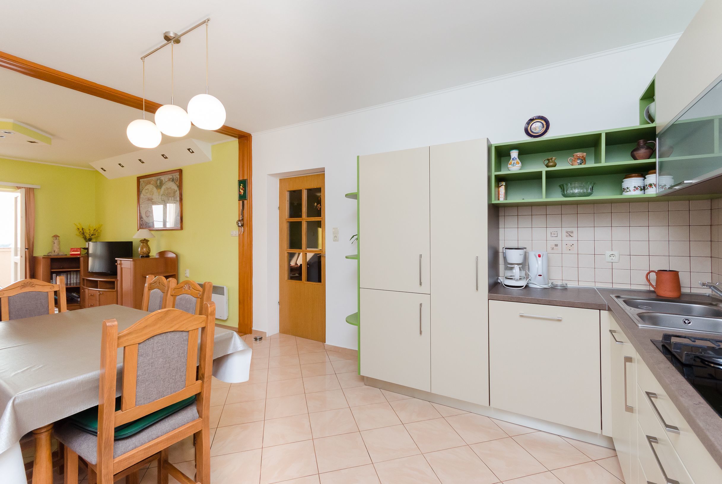 Una cocina con zona de comedor, con una mesa y sillas, una cafetera y un lavabo.